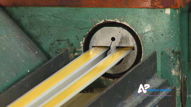 Grey and yellow plastic profile emerging from a round extrusion die