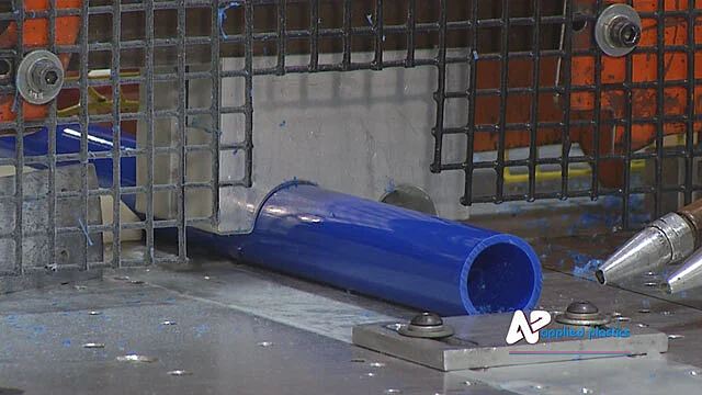 Blue plastic pipe on a cutting machine bed with shavings