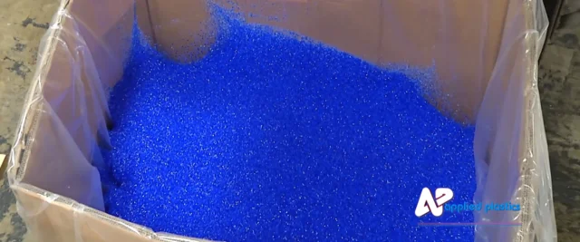 Blue plastic resin pellets filling a lined shipping box