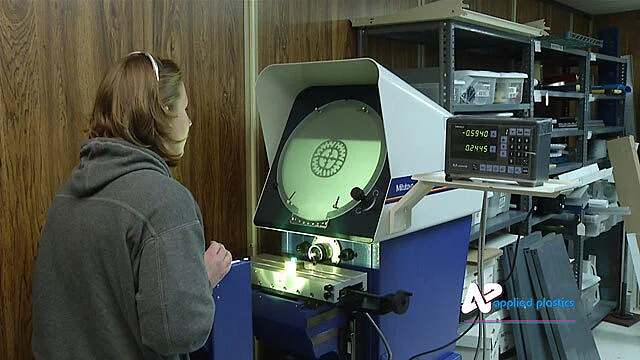 Technician inspecting a part profile on an optical comparator screen