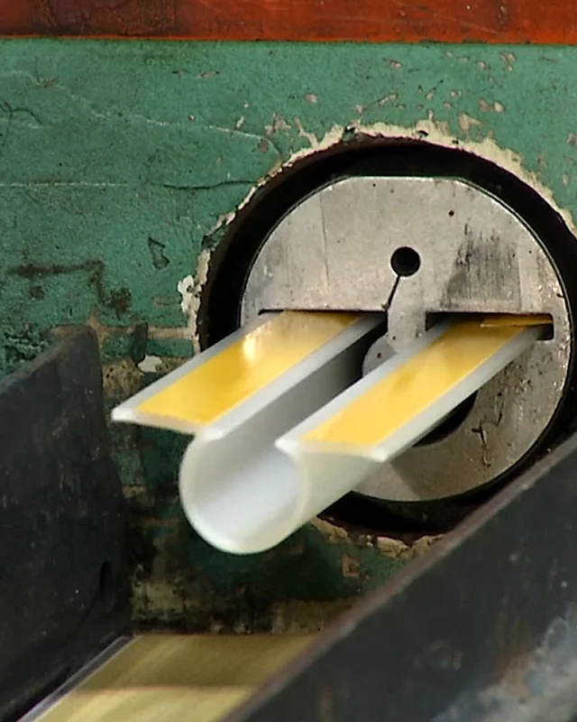 Close-up of a white and yellow profile leaving the extrusion die face