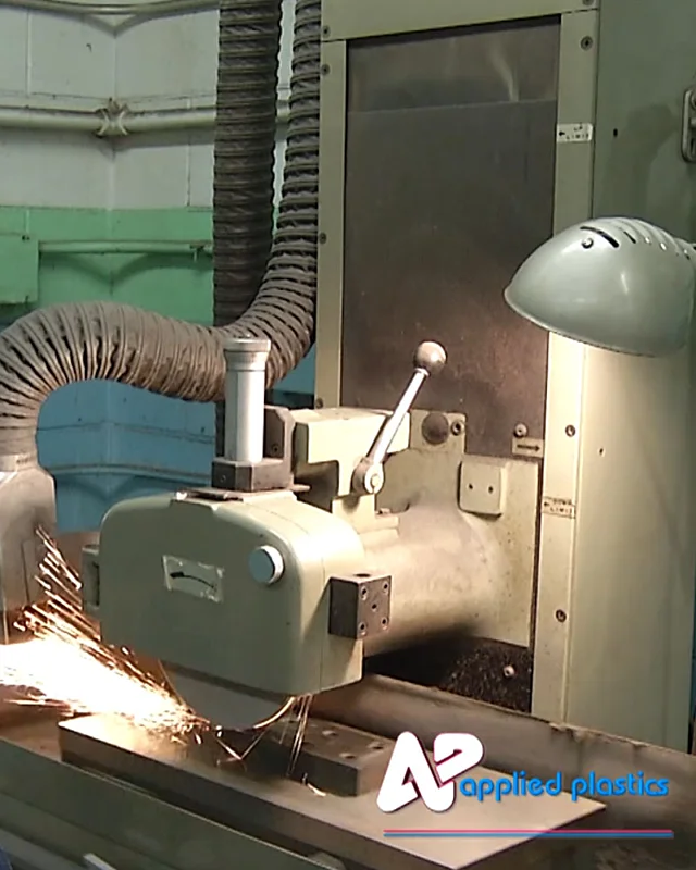 Surface grinder throwing sparks while machining a steel tooling plate