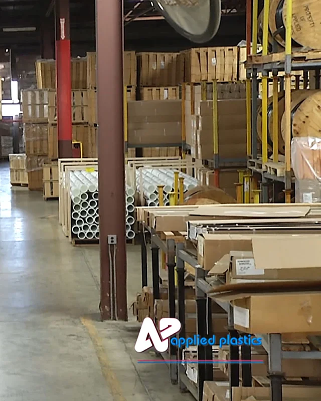 Warehouse racking holding cartons, crates and stacked white plastic tubes