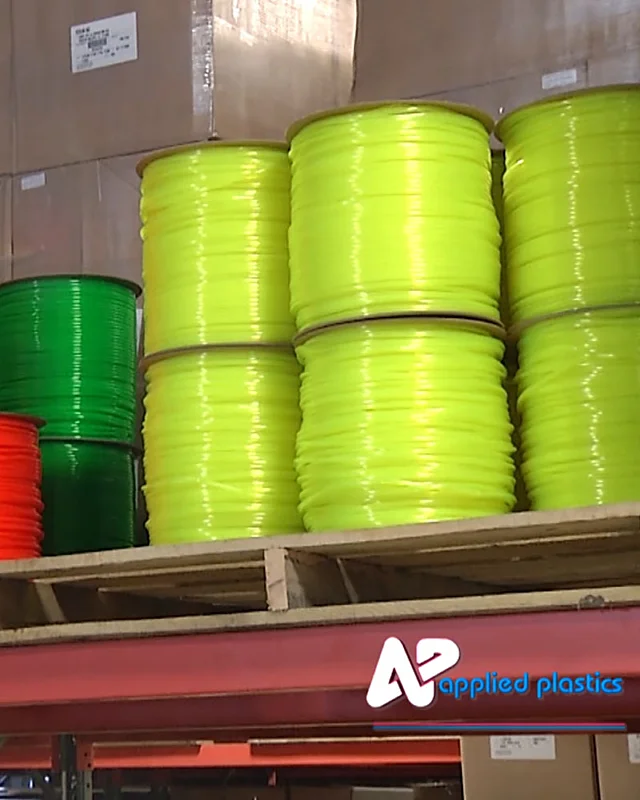 Spools of yellow, green and orange extruded plastic cord on warehouse racking